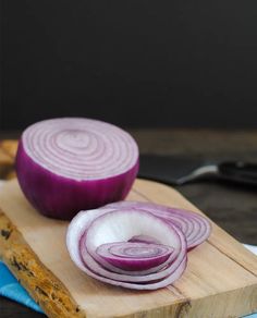 two onions on a wooden cutting board next to a knife