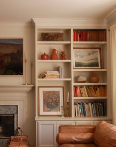 a living room filled with furniture and bookshelves next to a fire place in front of a fireplace