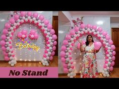 a woman standing in front of a pink and white balloon arch with balloons on it