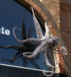 an octopus sculpture is displayed in front of the entrance to a building that has a sign on it