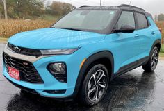 a blue suv parked in a parking lot on a rainy day with corn behind it