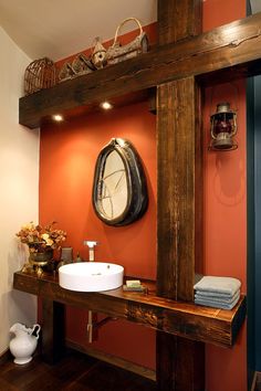 a bathroom with orange walls and wooden beams on the wall, along with a white sink