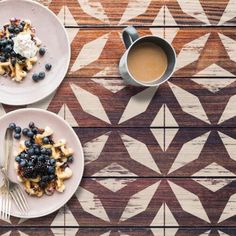 two white plates topped with waffles and blueberries next to a cup of coffee