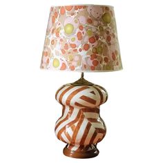 a lamp that is sitting on top of a wooden base with a pink and orange shade