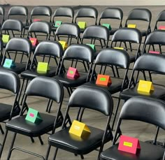 rows of black chairs with colored sticky notes on them