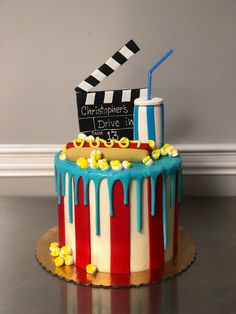 a cake decorated to look like a movie clapper and popcorn bucket with blue drips