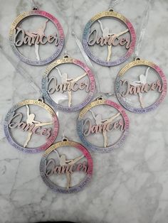 four ornament shaped like the word dance on a marble surface with ribbons around them