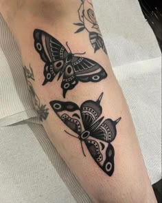 a close up of a person's leg with tattoos on it and moths in the background