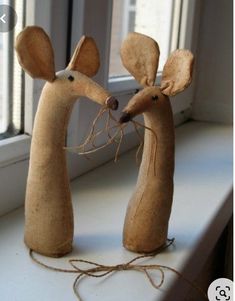 two wooden mice standing next to each other on a window sill with twine