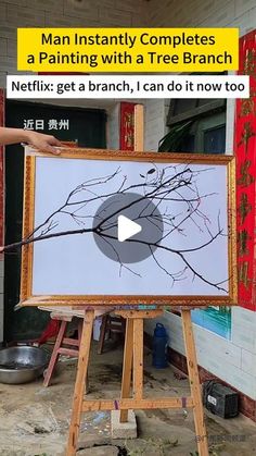 a man is painting with a tree branch