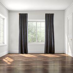 an empty room with wood floors and black curtains