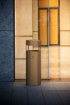 an empty trash can sitting in front of a building with glass doors on the outside