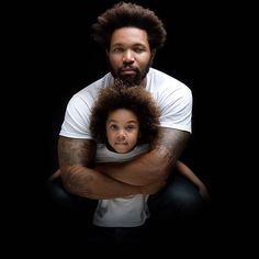 a man holding a young child in his arms with an afro haircut on their head