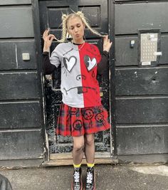 a young woman standing in front of a door wearing a red and grey shirt with an angry face on it