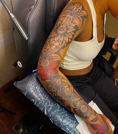 a woman sitting in a chair with tattoos on her arm