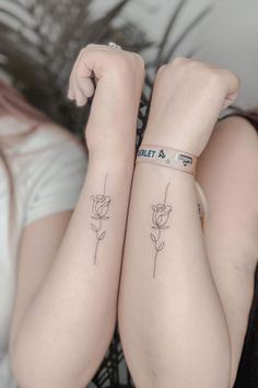 two women with matching tattoos on their arms, one has a flower tattoo on her arm