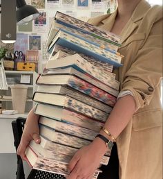 a woman holding a stack of books in her hands