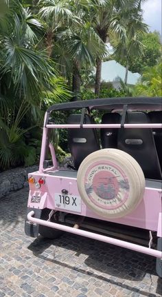 a pink jeep parked in front of some palm trees