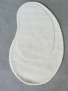 an oval white rug on a gray surface