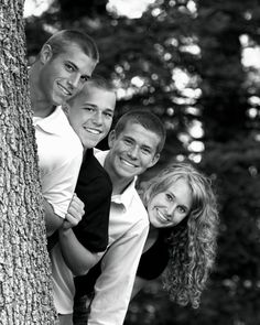 three people are standing next to each other near a tree and smiling at the camera