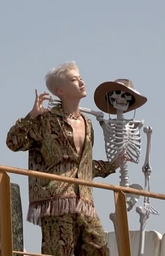 a man with white hair standing next to a skeleton on top of a wooden structure