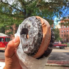 a person holding up a doughnut with chocolate frosting