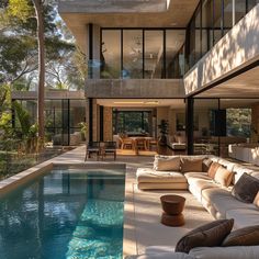 an outdoor living area with couches and tables next to a swimming pool in front of a house