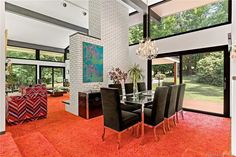 a dining room with red carpet and glass table surrounded by black chairs in front of large windows