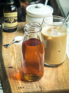 two jars filled with liquid sitting on top of a wooden cutting board