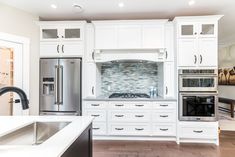 a kitchen with white cabinets and stainless steel appliances in it's center island area