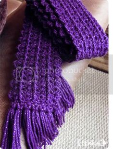 a purple knitted scarf laying on top of a pillow