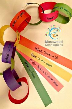 a rainbow colored paper circle with words on it and some ribbons hanging from the center