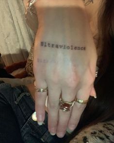 a woman's left hand with the word love written on it and two gold rings around her wrist