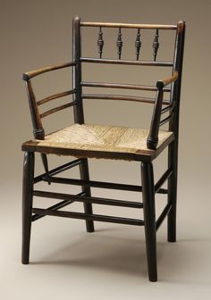 an old wooden chair with woven seat and back rests on a plain surface in front of a gray background