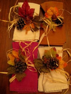 three napkins decorated with autumn leaves and pine cones on top of each other, sitting on a wooden table