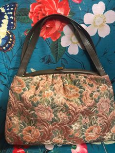 "Vintage 60s brown tapestry purse has beautiful rose pattern in mocha brown, peach, green and ivory. Purse has faux leather handles and trim. Purse is lined with vinyl and has a clear plastic attached coin purse which would also be perfect for ID card. Brass tone metal clasp shows wear otherwise purse is in excellent condition. No Label Purse measures 13\" side to side, @ 9\" tall and 4\" across bottom. Strap is 17\" across." Vintage Beige Tapestry Bag, Vintage Tapestry Bag For Everyday, Vintage Tapestry Tote Bag, Vintage Tapestry Satchel With Top Handle, Vintage Tapestry Satchel With Top Carry Handle, Vintage Tapestry Bag With Detachable Handle, Vintage Satchel Shoulder Bag With Rolled Handles, Vintage Brown Tapestry Satchel, Retro Rectangular Tapestry Bags