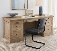 a chair sitting at a desk with a lamp on top of it and a painting hanging above the desk