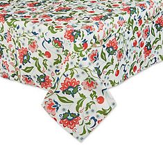 a white table cloth with red and green flowers on it, sitting on top of a wooden table