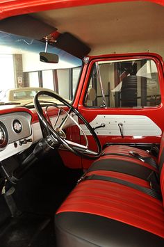 the interior of an old red truck with black leather seats