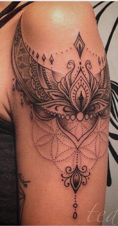 a woman's shoulder with an intricate tattoo design on the back of her arm