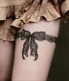 a woman with a tattoo on her thigh that has a bow tied around it's waist