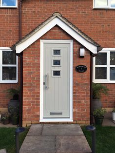 a grey front door on a red brick house with white trim and window panes