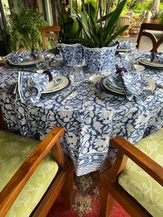 a blue and white table cloth on top of a dining room table with place settings