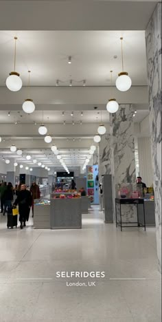 the interior of a store with marble floors and lights hanging from the ceiling, along with people shopping