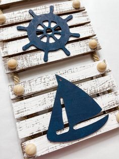 two wooden planks are decorated with blue and white wood cutouts, one is a sailboat and the other is a ship