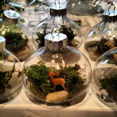 several glass ornaments with plants and animals in them on a tablecloth covered table cloth