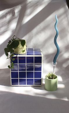 a blue and white vase sitting on top of a table next to a potted plant