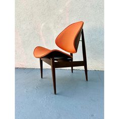 an orange chair sitting on top of a cement floor next to a white stucco wall