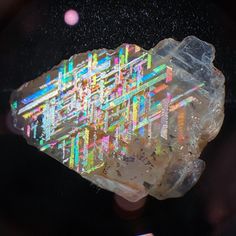 a piece of crystal with multicolored lines on it's surface in front of a black background