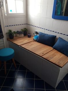 a blue and white tiled bathroom with a wooden bench in the corner next to a window